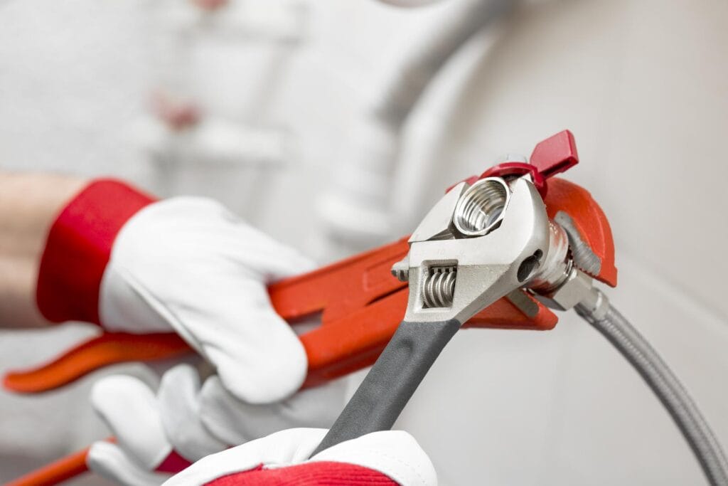 Plumber holding pipe wrenches for an emergency repair in Erie