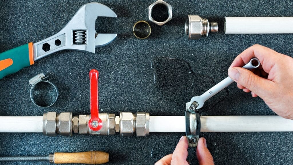 Plumber repairing a pipe valve with an adjustable wrench in Erie