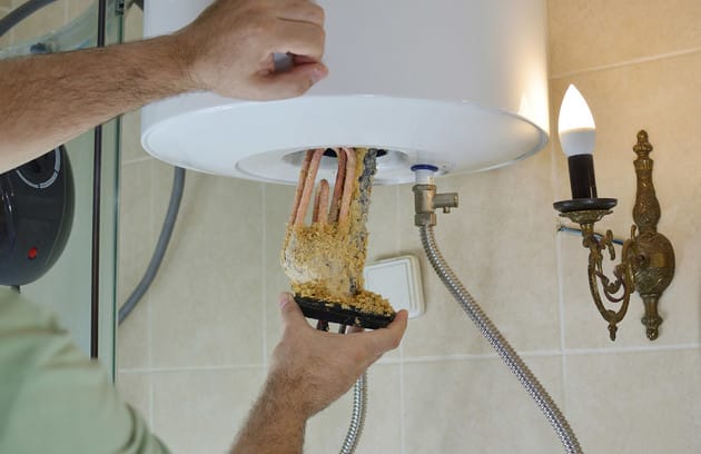 Technician removing mineral buildup from a water heater in Erie
