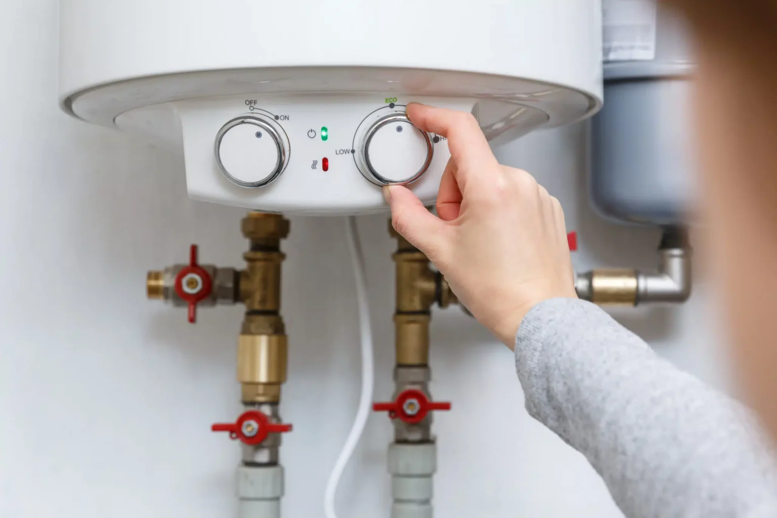 Homeowner adjusting the temperature controls on a water heater in Erie